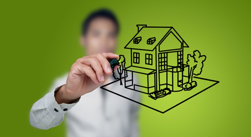 Man drawing a image of a house with black marker over a green background
