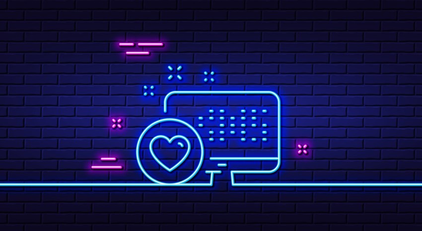 Neon graphic of a laptop with a heart over a blue brick wall