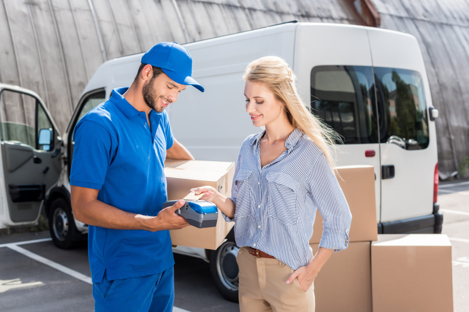 Male delivery man dropping of a shipment to a female who is paying via credit card