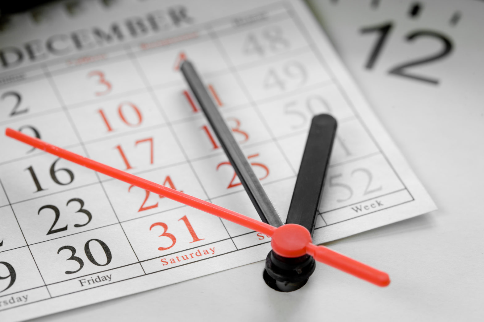 Clock arms over a December calendar