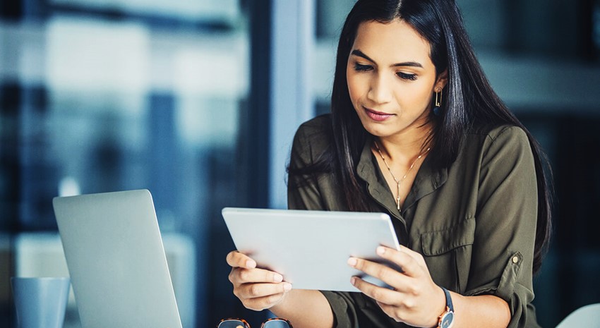 Woman working at her desk holding her tablet of Business Central