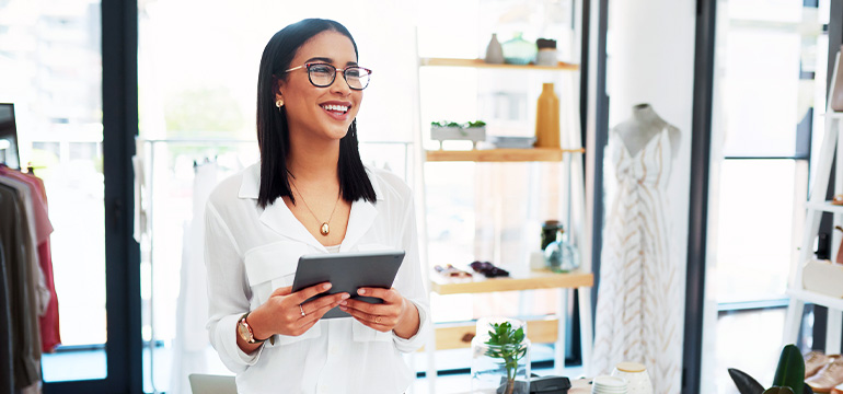 Female retail employee or owner holding a tablet and smiling in her retail store