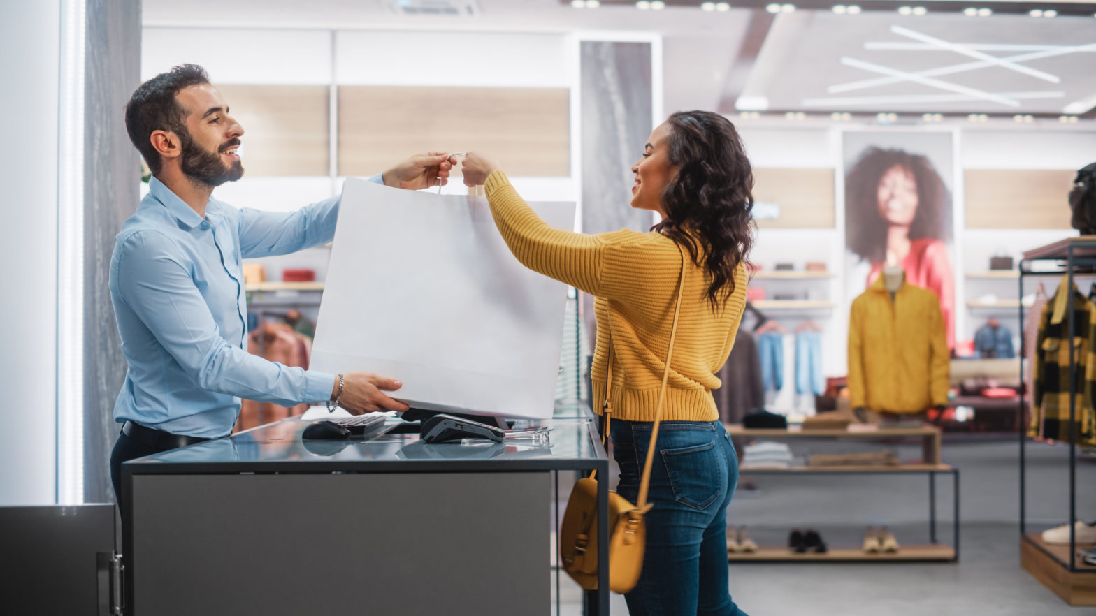 Retail employee handing purchase over to young female shopper