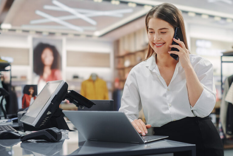 Female retail business owner on her laptop in store and on the phone