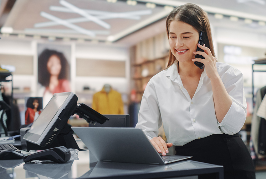 Female retail business owner on her laptop in store and on the phone